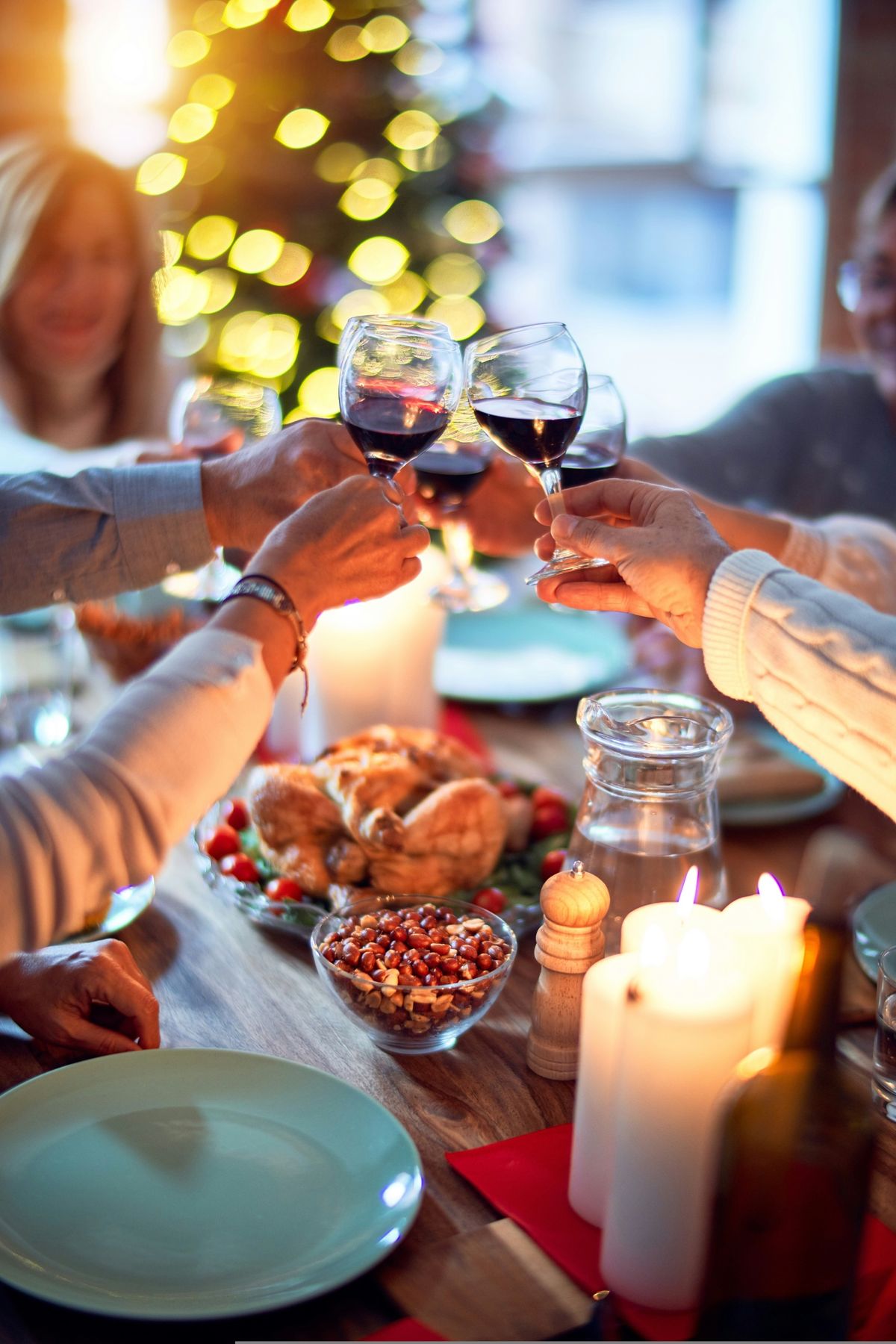 Gäste stoßen an einer weihnachtlich gedeckten Tafel mit Rotwein an